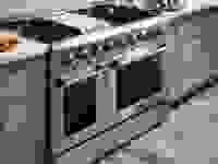 一个不锈钢的，专业级的双烤箱炉灶是明亮的现代厨房。