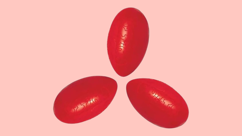 Three red, egg-shaped Silly Putty containers on a pink background.