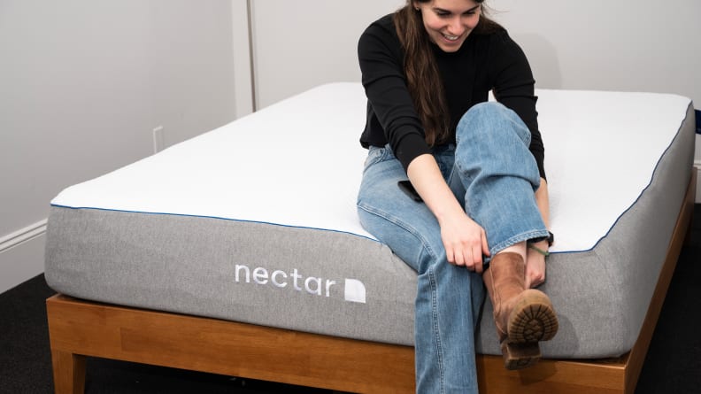 a woman sits on the edge of the nectar mattress
