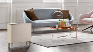A gold air purifier stands in a living room in front of a blue couch