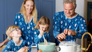 A family dressed in matching Hanukkah pajamas cooking in the kitchen