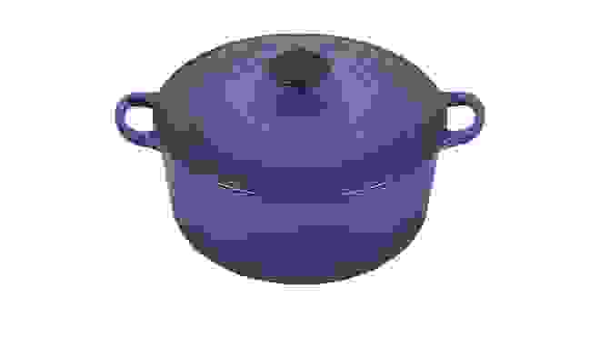 Blue ceramic dutch oven in front of white background.