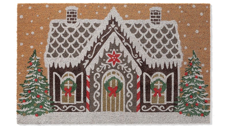 This holiday doormat features a quaint gingerbread house.
