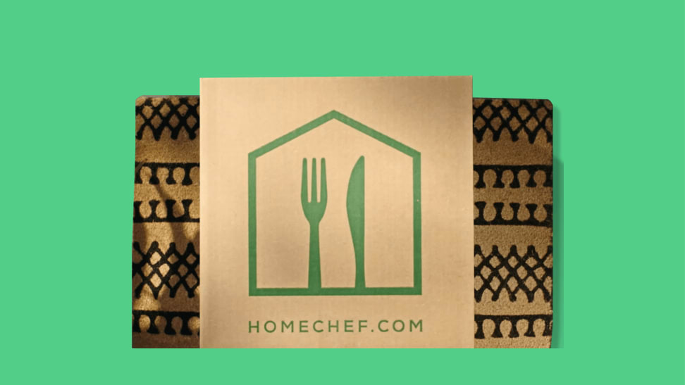 A Home Chef delivery box on a door mat in front of a colored background.
