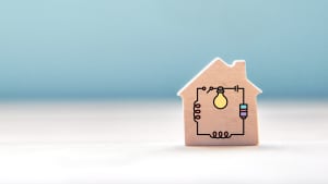 A small wooden toy house block with an electrical circuit graphic overlay