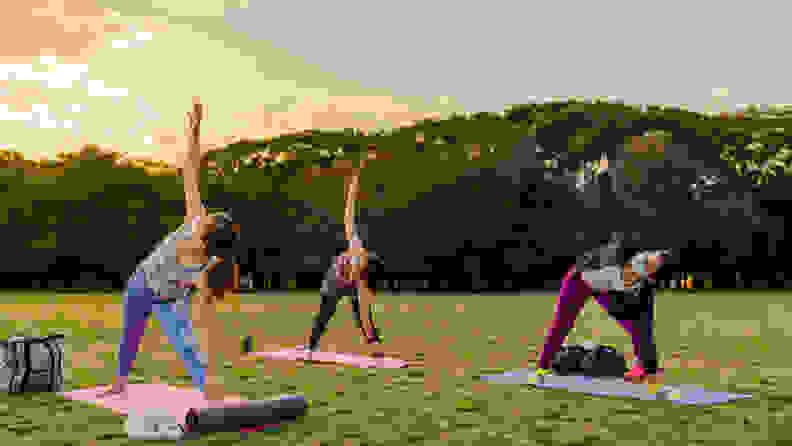 three women doing yoga in a park