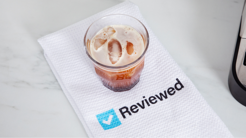 A cup of coffee on top of a napkin with the Reviewed logo.