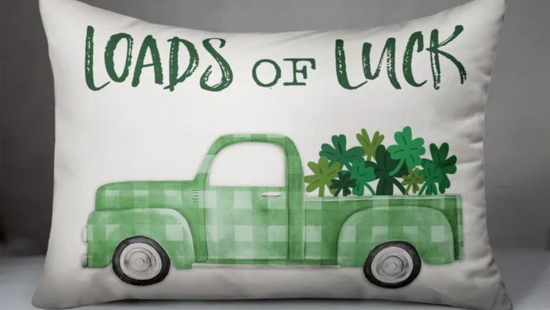 A white pillow from Wayfair with a green truck on it that reads "loads of luck"