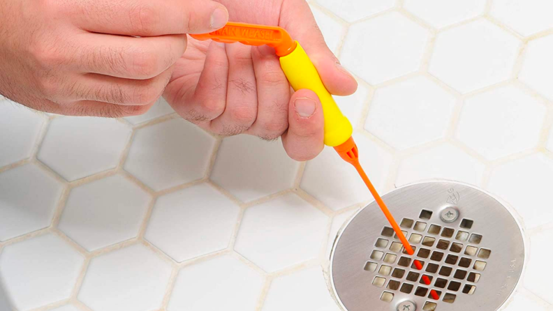 A person pulls hair out of a drain with a FlexiSnake.