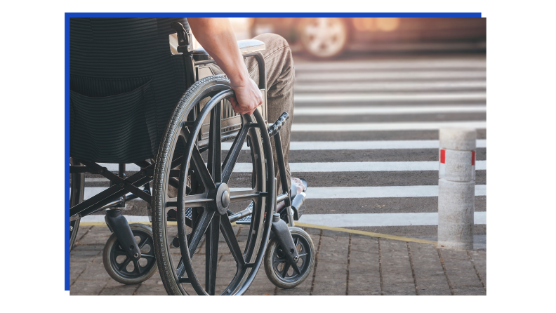 Person sitting in wheelchair on curb waiting to enter crosswalk.