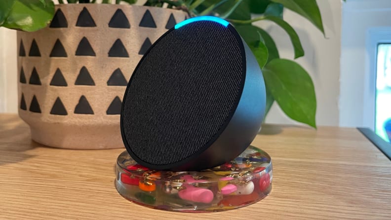 The Echo Pop smart speaker turned to the side and displayed on a wood table