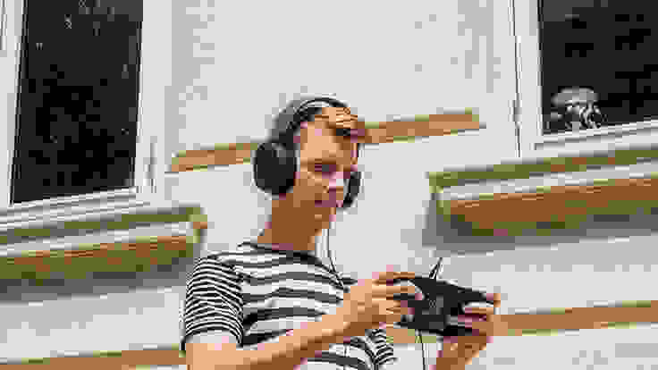 A person wearing the Steelseries Arctis 3 stand in front of a beige building while playing the Nintendo Switch.