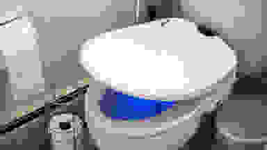 A bidet attachment on a toilet. The bowl glows mysteriously blue.