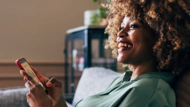Happy woman sitting with phone in hand using the Babbel app