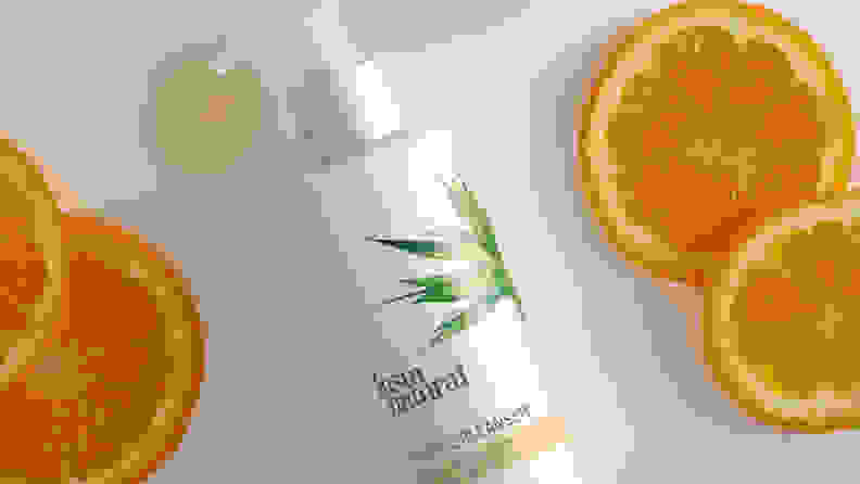 The InstaNatural Vitamin C Cleanser on a white background with orange slices surrounding it and a dollop of product pooling below the pump.