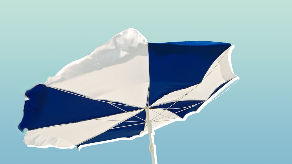 A blue and white striped umbrella blows in the wind.