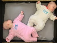 Two babies wearing Baby Merlin’s Magic Sleepsuit lay down for a nap.