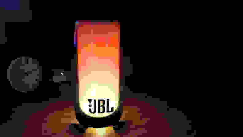 The JBL Pulse 5 shown playing a lava lamp effect in a dark room.
