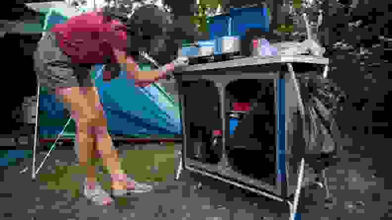 A woman adjusts a camp stove