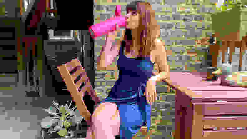 The author takes a sip out of her water bottle in a patio setting.