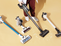 Four cordless vacuums on a brown background with legs of one person who is vacuuming