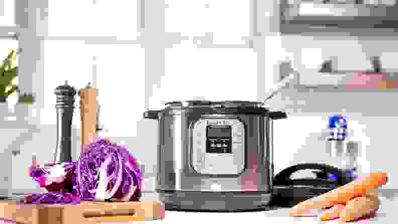 Instant pot in a kitchen surrounded by veggies