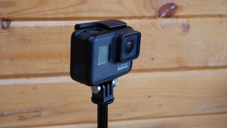 Close up of a GoPro camera against a paneled wall.