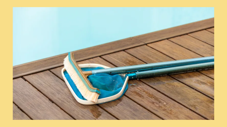 A pool brush laying next to a pool.
