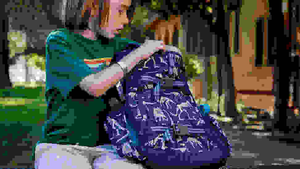 Little boy looking in his school backpack.