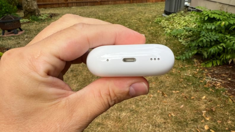 A hand holding the Apple AirPods Pro 2 charging case showing its USB-C charge port.