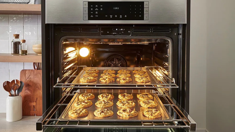 Bosch HBL8454UC door open with cookies on baking sheet on top and bottom rack.