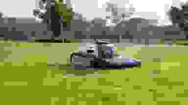 Small black and white robotic lawnmower sitting stationary in a field of grass