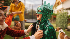 A young  boy dressed in a green dinosaur costume laughing