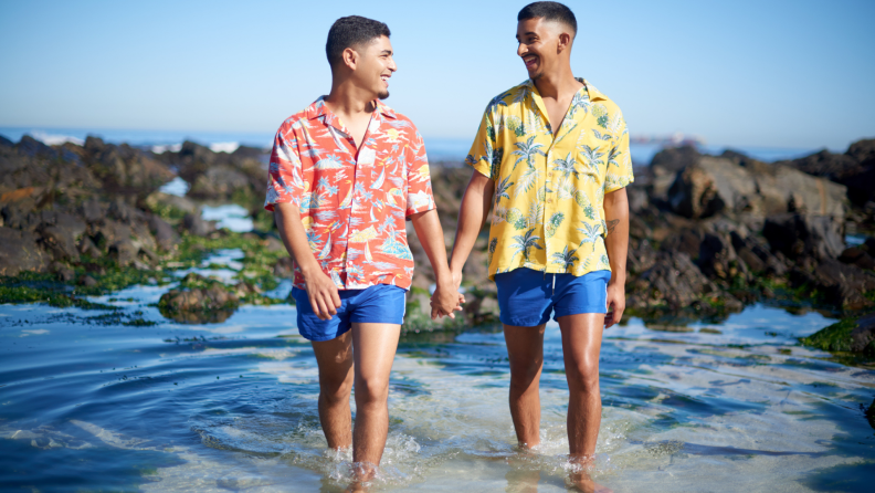 A couple holds hands while wading in shallow water.