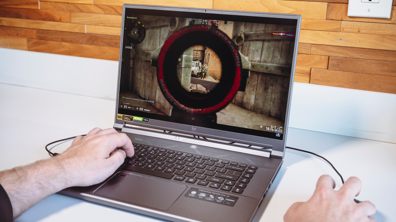 Person using fingers to play virtual game on laptop computer.