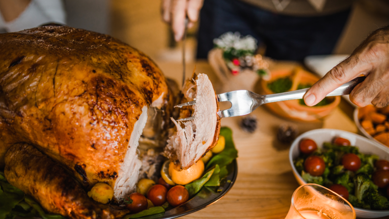 A person carving into a Thanksgiving turkey.