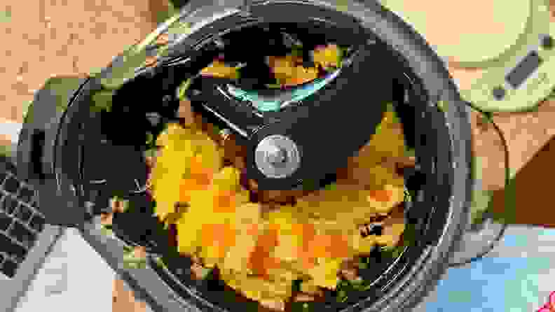 The juicing chamber is exposed after removing the top lid. There are large chunks of fruits, mainly pineapples, around the auger that are unjuiced.