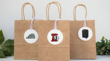 Three brown gift bags on a table with gift tags on them
