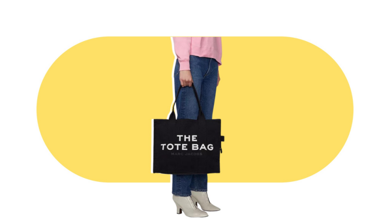 A model holding a black tote bag that is printed with text that reads “The Tote Bag.”