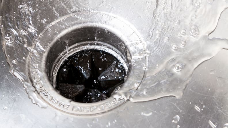 Water running from kitchen faucet in sink into drain.