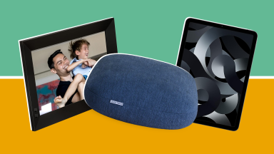 Digital picture frame with parent and child smiling together inside the black frame next to navy blue weighted pillow next to black Apple iPad tablet.