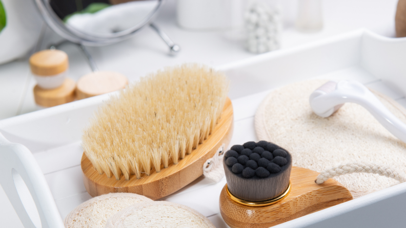 A brush laying next to other skincare tools on top of a vanity