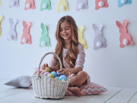 A girl sitting on the floor putting eggs in her Easter basket