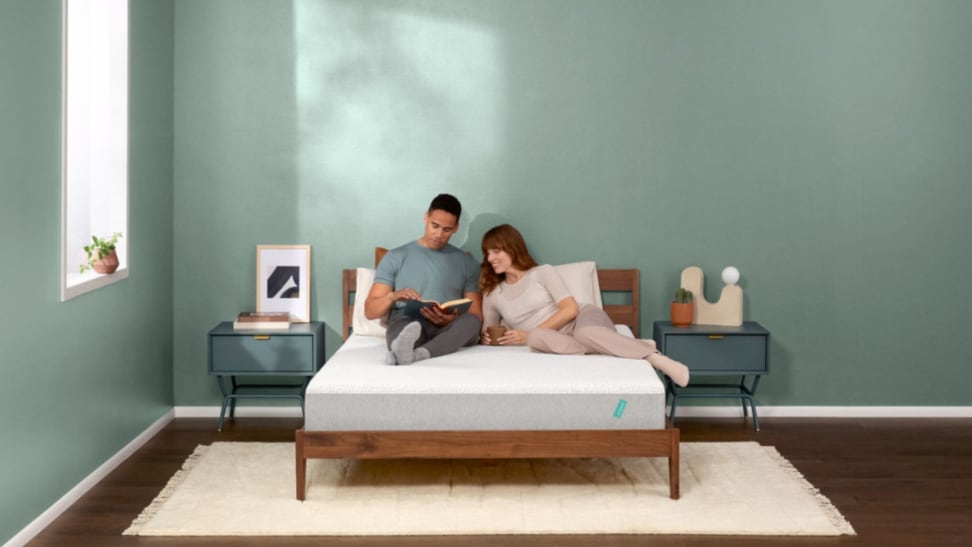 A couple sitting on a Tuft and Needle mattress.