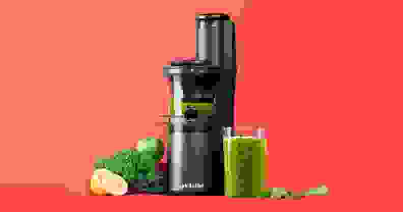 A NutriBullet Slow Juicer is in the center, grinding green juice with green vegetables surrounding it.