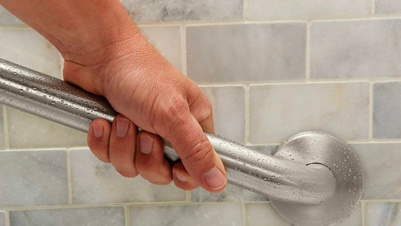 A person grabs onto a bathroom railing.