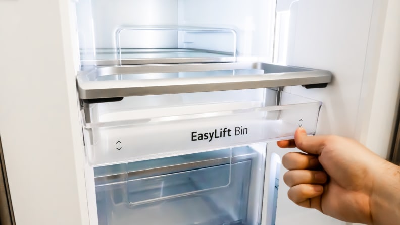 A close-up of a hand lifting up the edge of the "EasyLift bin" in the LG LRMVS3006S french door refrigerator