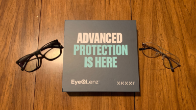 Two pairs of glasses on a wooden surface, along with a box that reads “Advanced protection is here, EyeQLenz Zenni.”