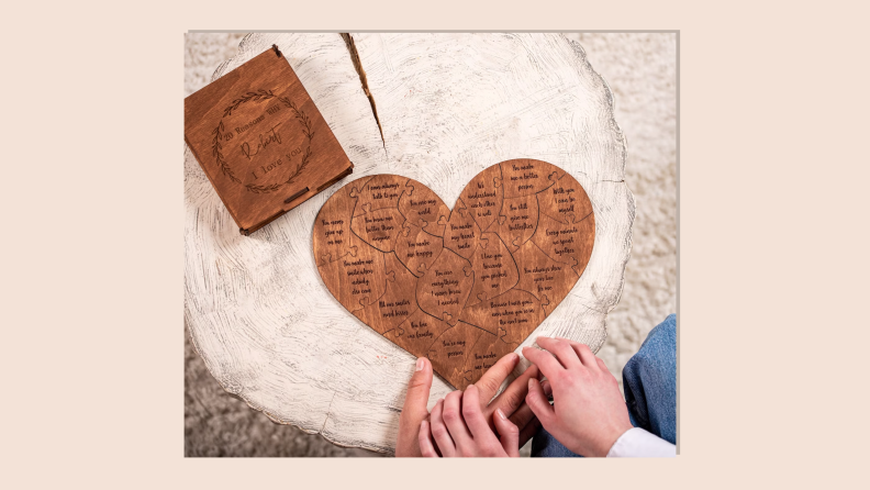 Three hands resting on a wooden log in front of a Reasons I Love You personalized wooden puzzle on tan background.