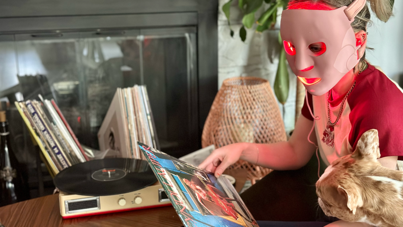 Woman wearing a red light mask and talking to a cat